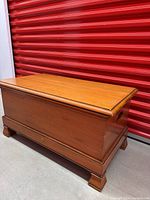 Full view of the wooden storage chest showing shape, finish, and feet.