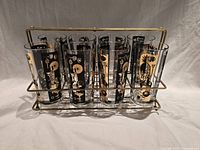 Front view of eight decorated tumblers in caddy