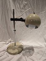 Full view of eyeball desk lamp showing base, chrome stem, adjustable shade and cord