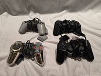 Group shot of four wired PlayStation controllers: two black, one grey, one gold chrome