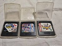 Front view of three Sega Game Gear cartridges in open clear cases