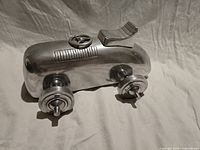 Left front perspective of polished cast aluminum model car showing steering wheel, seat and wheels