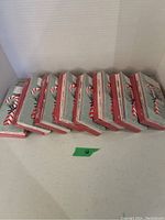 Eight packages of Christmas cards stacked horizontally showing the side with red and green striped pattern and a candy cane design