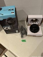 Blue Snowball iCE black desktop microphone shown outside the box with tripod stand wrapped in bubble wrap beside it.