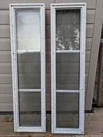 Front view of two exterior door window inserts side by side, showing white frames and divided glass panes.