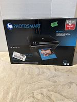 Boxed HP Photosmart printer with branding and photo on box shown.