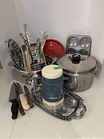 Photo of the full lot showing the Thermos jug, muffin pan, loaf pan with lid, trays, strainer, and various kitchen utensils.