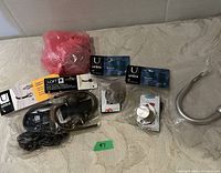 Wide view of assorted wall hooks and holdbacks laid on surface, some in packaging from Umbra and Loft brands.