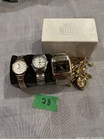 Four watches displayed, including one in a white Nolan Miller box with 'Ultimate Collection' branding