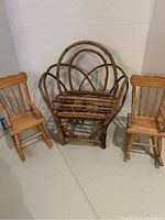 Handmade toy bench crafted from woven wood twigs/logs flanked by two small light wood toy rocking chairs.