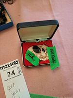 Open jewelry box containing necklace pendant and earrings with green 14k labels