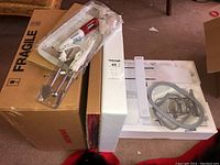 Overview of foam casing, cardboard box labeled Fragile and items inside including extension module parts and soldering gun