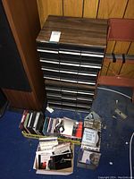 Full view of stacked cases with multiple drawers for cassette tapes and boxes of CDs on the floor.