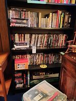 Four shelves filled with DVDs, VHS tapes, and CDs organized vertically and horizontally