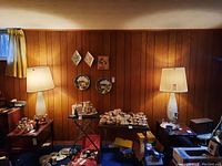 Two matching table lamps on wood-paneled background among other basement items
