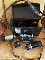Camera body, three lenses and leather case arranged on chair