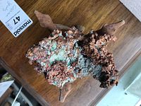 Copper-colored mineral rock specimen showing textured surface with greenish-blue oxidation, likely chalcopyrite