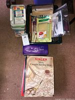 Photo of vintage Singer sewing books stacked near sewing supplies and storage containers.