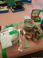 Overall view of glass bowl with sterling silver lid, napkin rings, coasters and spoons on table