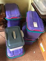 Stack of four purple plastic bins with teal and pink lids