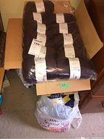 Multiple chocolate brown yarn balls in sealed plastic bag on box