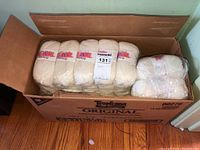 Box with two rows of multiple bundles of yarn, each bundle containing six skeins wrapped in plastic.