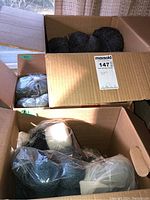 Three cardboard boxes filled with yarn skeins in various colors and textures
