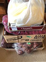 Three stacked boxes filled with yarn skeins mostly in red hues, plastic bag partially covering top box.