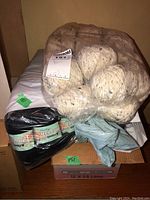 Overview of yarn balls packed in plastic, including 3 smaller dark green yarn bundles.