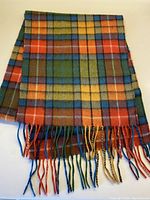 Full view of the multi-color plaid cashmere scarf folded showing pattern and fringed ends.