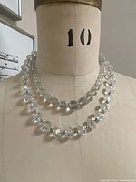 Two clear crystal necklaces displayed on a mannequin bust showing length difference and overall look.