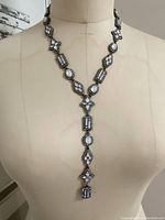 Full view of the iridescent stone drop strand necklace on a dress form showing the length and drop strand to the bust line.