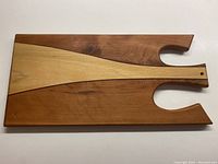 Full view of the wooden cheese/charcuterie board showing tri-wood design and handle with cutouts.