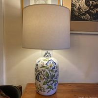 Front view of full lamp with white fabric shade showing entire floral design and lamp height.