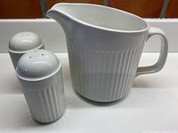 Three-piece set of white Johnson Bros. Athena serving pieces showing a large pitcher with vertical ribbed pattern and a pair of salt and pepper shakers.