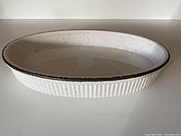 Oven-to-table oval casserole dish with ribbed cream ceramic with cinnamon speckles and uneven cinnamon rim