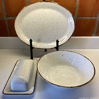 Set of three ceramic serving pieces: oval platter on stand, large bowl, and covered butter dish shown together.