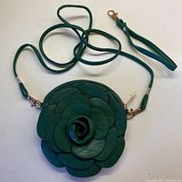 Front view of real leather round crossbody bag showing detailed layered rose petal design in green.