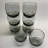 Eight smoky grey roly poly lowball glasses stacked and displayed to show shape and quantity.