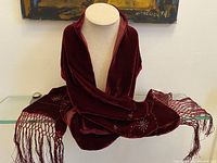 Full view of cherry red velvet scarf draped over mannequin showcasing length, fringe, and beadwork at ends.