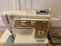 Full side view of Singer Model 750 sewing machine showing body shape, spool pin with blue thread, dials and controls, and power cord.