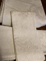 Close-up of folded napkins showing delicate floral and leafy damask pattern in pure white Irish linen.