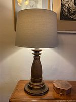 Full view of the vintage table lamp showing the oak base and pale tea lampshade on a wooden surface.