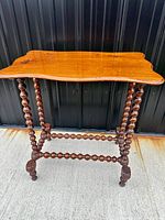 Full view of antique barley twist wooden table with shaped rectangular top and intricate twisted legs and stretchers.