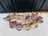 Full view of the brutalist styled metal fish wall art sculpture showing the entire piece with multiple fish shapes connected, finished in rust and bronze tones.