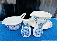 Overview of all pieces showing gravy boat, pitcher with plate, and salt and pepper shakers with colorful mid-century modern floral and character designs in blue, green, and purple.
