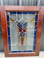 Full front view of stained glass panel in wooden frame showing complete geometric design