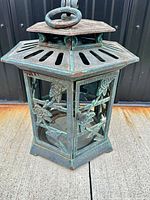 Full view of hexagonal iron garden lantern with floral rose cutouts and patina