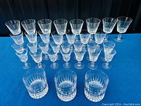 Full display of vintage cut crystal stemware and glasses showing multiple stemmed glasses and three rocks glasses in front.