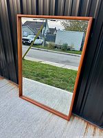 Full front view of the large rectangular mirror with teak frame showing clear glass and warm wood tone.